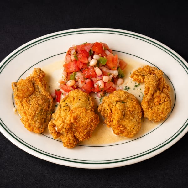 Four golden-fried oysters with a side of fresh tomato and corn salsa on a white plate.