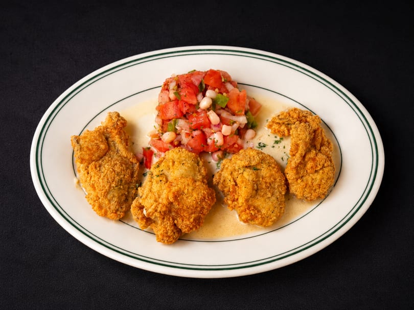 Four golden-fried oysters with a side of fresh tomato and corn salsa on a white plate.