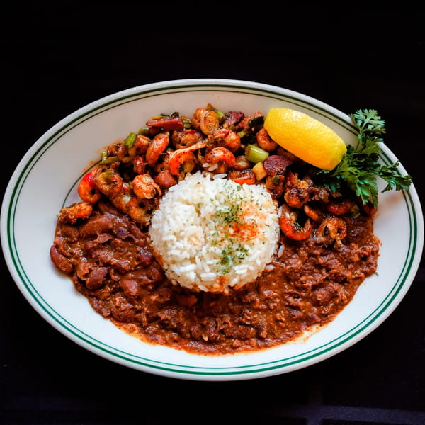 Cajun dish with shrimp, red beans and rice, garnished with lemon and parsley.