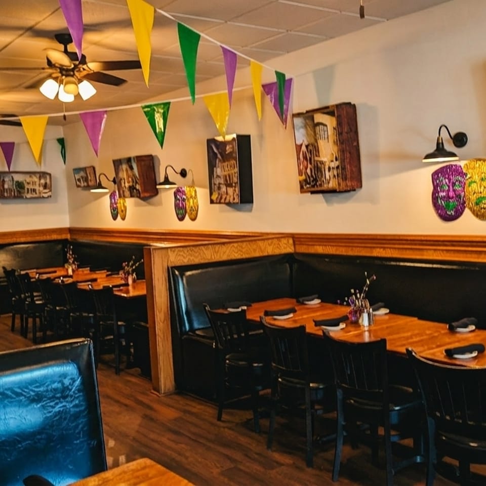 Restaurant interior with Mardi Gras decorations, black booths, wooden tables, and artwork on the walls.